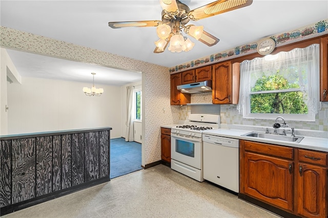 kitchen featuring backsplash, ceiling fan with notable chandelier, white appliances, sink, and pendant lighting