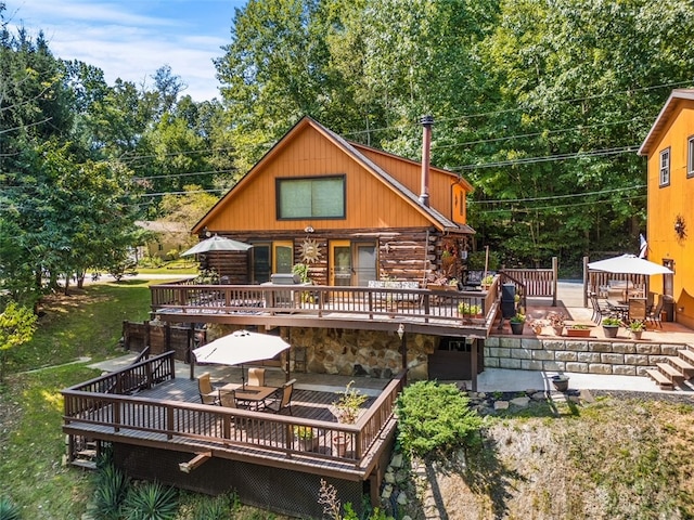 back of property featuring a wooden deck and a patio