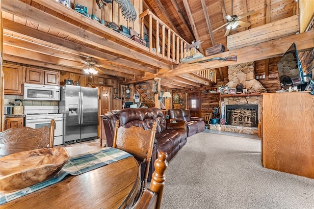 carpeted dining space featuring wooden ceiling, beam ceiling, ceiling fan, and a stone fireplace