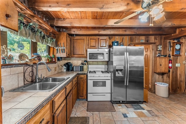 kitchen with beamed ceiling, white appliances, tile countertops, sink, and ceiling fan