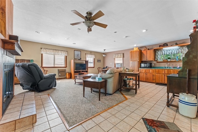 living room featuring sink, light tile patterned floors, ceiling fan, and a tile fireplace