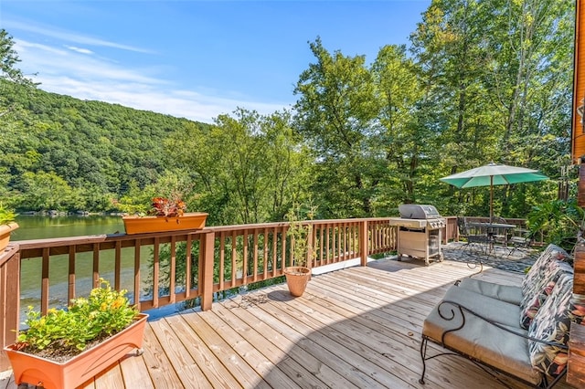 wooden terrace with area for grilling and a water view