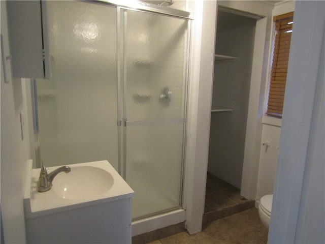 bathroom with a shower with shower door, toilet, vanity, and tile patterned floors