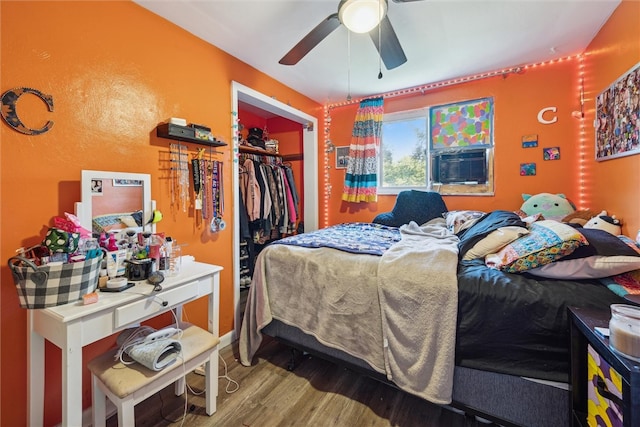 bedroom with cooling unit, ceiling fan, a closet, and wood-type flooring