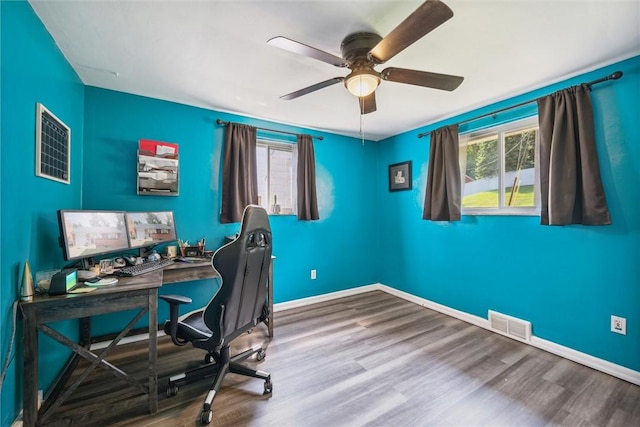 unfurnished office featuring visible vents, baseboards, ceiling fan, and wood finished floors