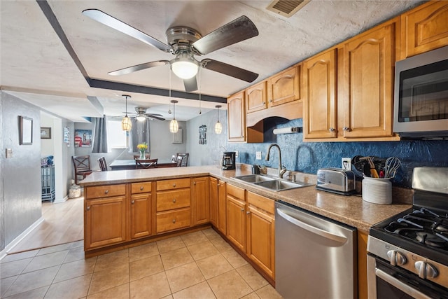 kitchen with appliances with stainless steel finishes, sink, kitchen peninsula, ceiling fan, and pendant lighting