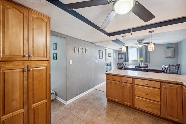 kitchen with brown cabinets, pendant lighting, light countertops, light tile patterned floors, and ceiling fan