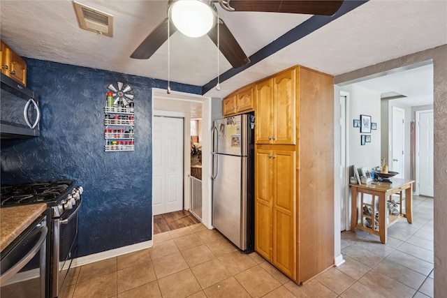 kitchen featuring stainless steel appliances, light tile patterned floors, and ceiling fan