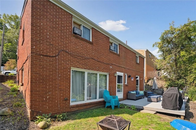 rear view of house featuring brick siding and an outdoor living space with a fire pit