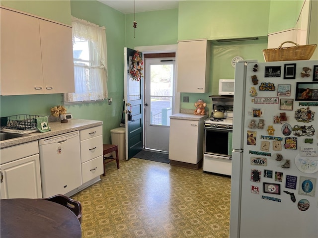 kitchen featuring plenty of natural light, white appliances, and white cabinets