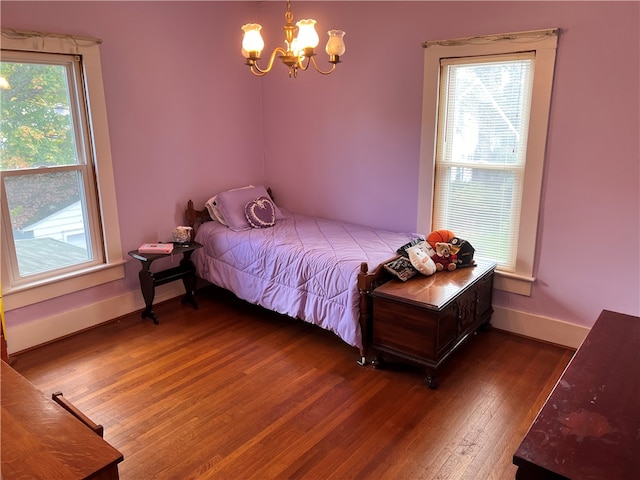 bedroom with wood-type flooring, an inviting chandelier, and multiple windows