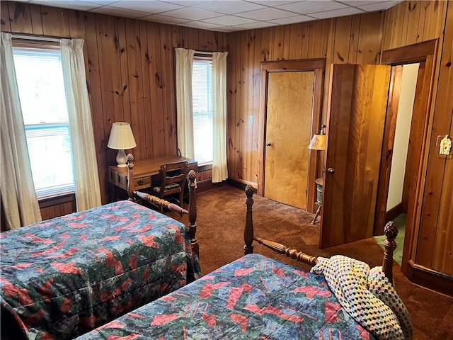 bedroom with wooden walls, a paneled ceiling, and carpet