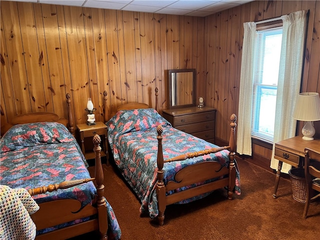 bedroom featuring a paneled ceiling, carpet flooring, and wooden walls