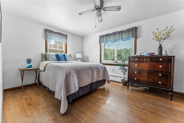 bedroom featuring wood-type flooring, a baseboard heating unit, and ceiling fan