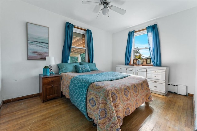 bedroom with wood-type flooring, ceiling fan, and baseboard heating