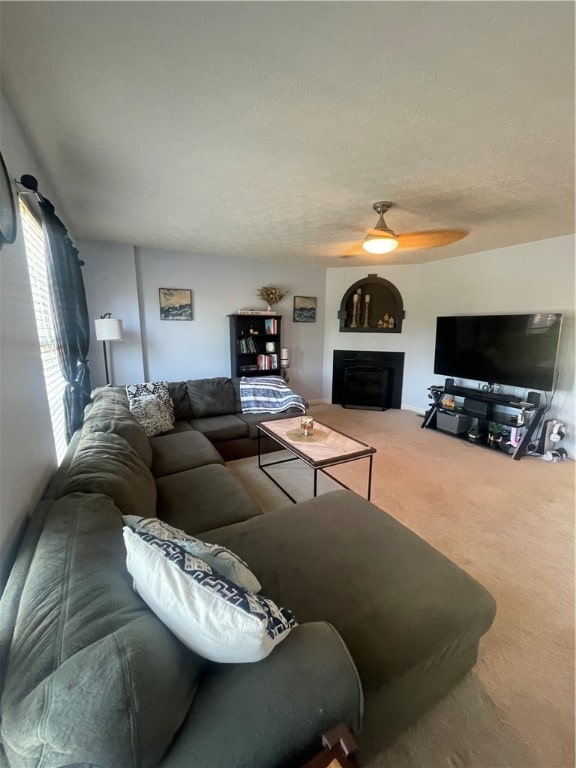 living room with a textured ceiling, carpet, and ceiling fan