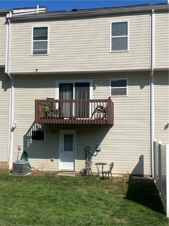 rear view of property with central AC and a lawn