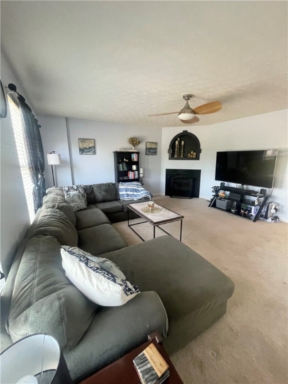 living room with ceiling fan, a textured ceiling, and carpet floors