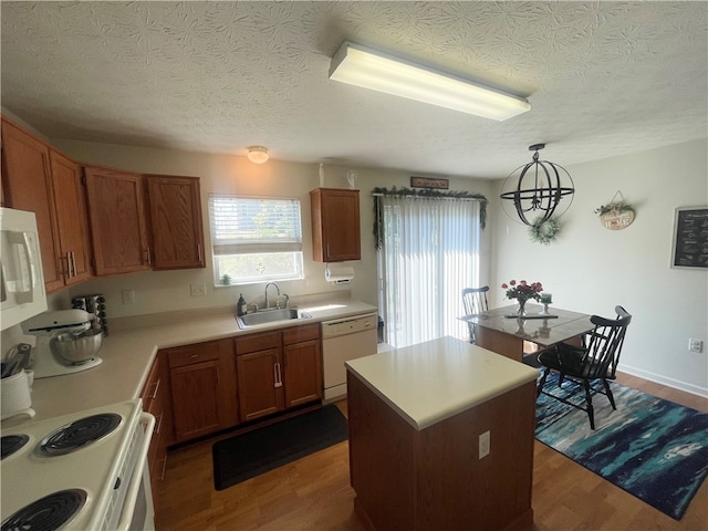 kitchen with a center island, white appliances, sink, dark hardwood / wood-style floors, and pendant lighting