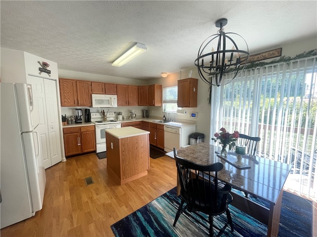 kitchen featuring light wood-type flooring, a notable chandelier, white appliances, sink, and a center island