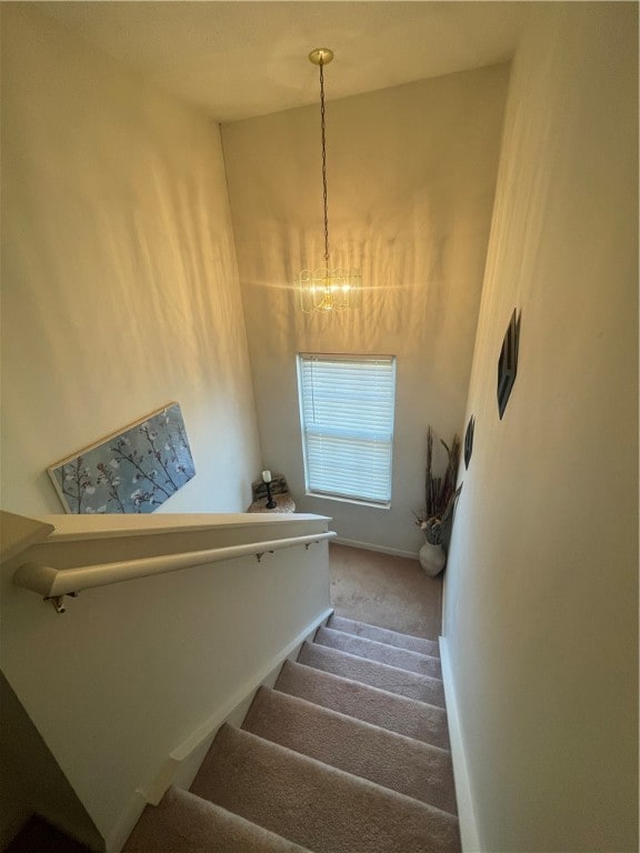 stairway with carpet and a notable chandelier