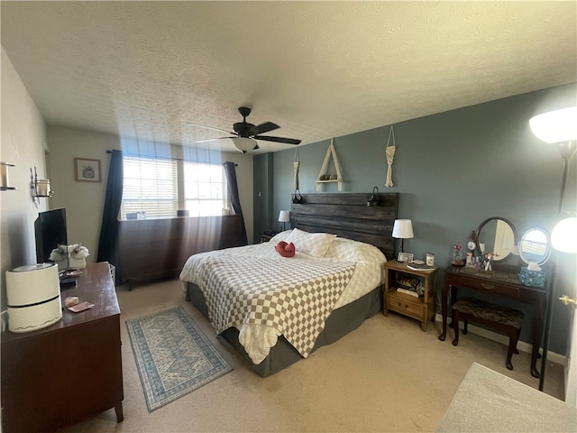 bedroom featuring a textured ceiling, light colored carpet, and ceiling fan