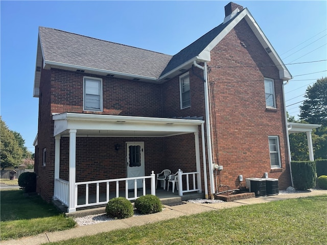 rear view of house featuring cooling unit and a yard