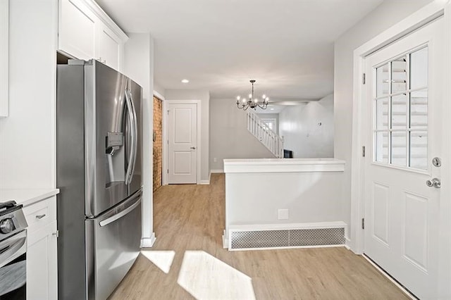 kitchen featuring light hardwood / wood-style flooring, a notable chandelier, appliances with stainless steel finishes, and white cabinets