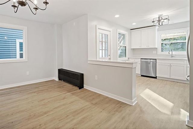 kitchen with radiator heating unit, white cabinetry, stainless steel dishwasher, and light hardwood / wood-style floors