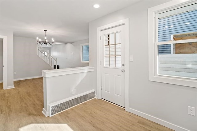 foyer entrance with light wood-type flooring and a chandelier