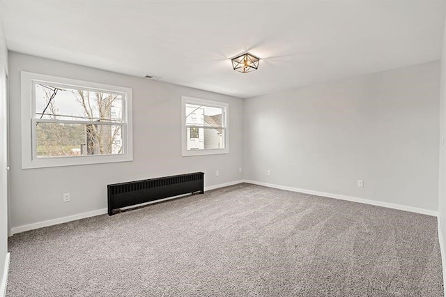 empty room featuring radiator heating unit and carpet flooring