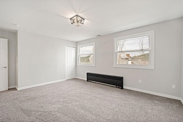 carpeted spare room featuring a wealth of natural light and radiator