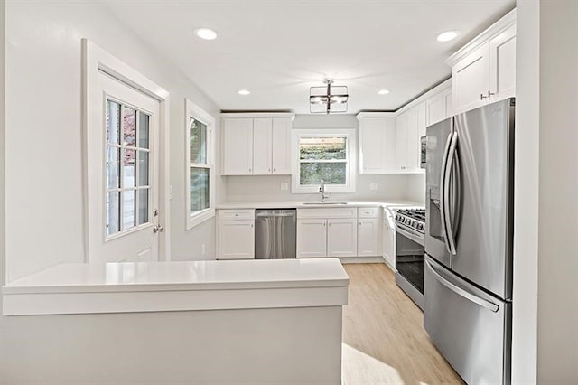 kitchen featuring stainless steel appliances, light hardwood / wood-style floors, and white cabinetry