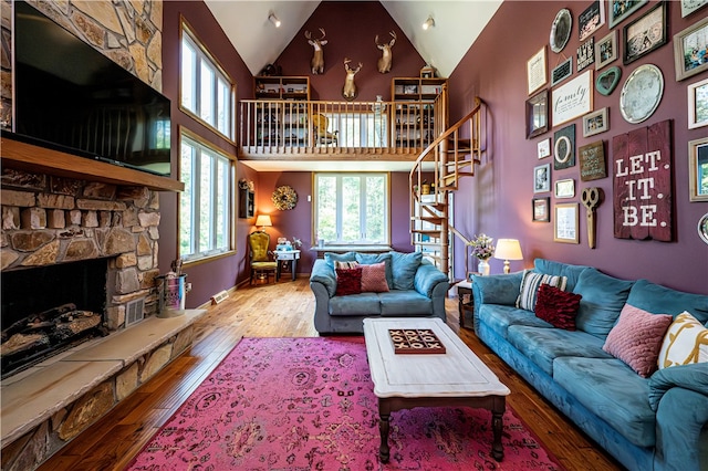 living room featuring a fireplace, high vaulted ceiling, and wood-type flooring