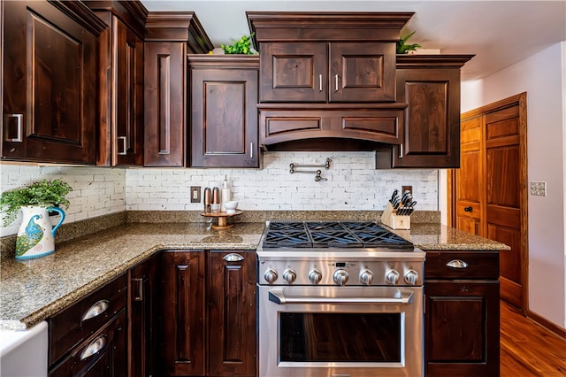 kitchen featuring dark hardwood / wood-style flooring, light stone countertops, high end stove, and custom exhaust hood