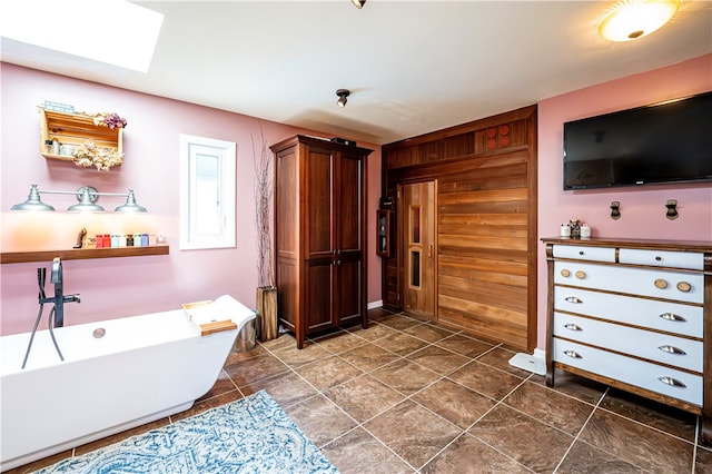 bathroom with vanity, wood walls, a bathing tub, and a skylight