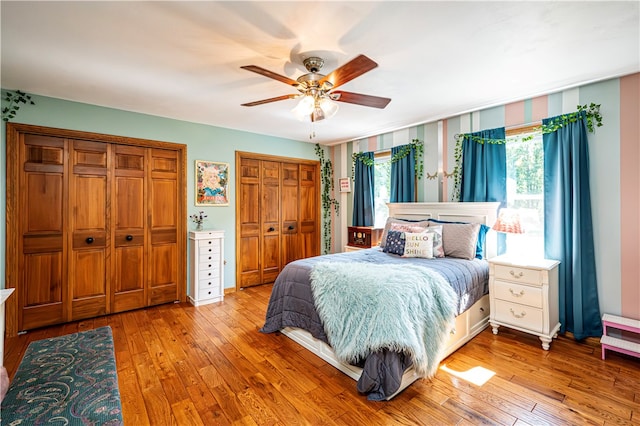 bedroom with two closets, light wood-type flooring, and multiple windows