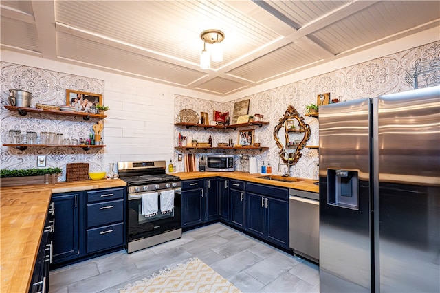 kitchen featuring stainless steel appliances, blue cabinets, and butcher block counters