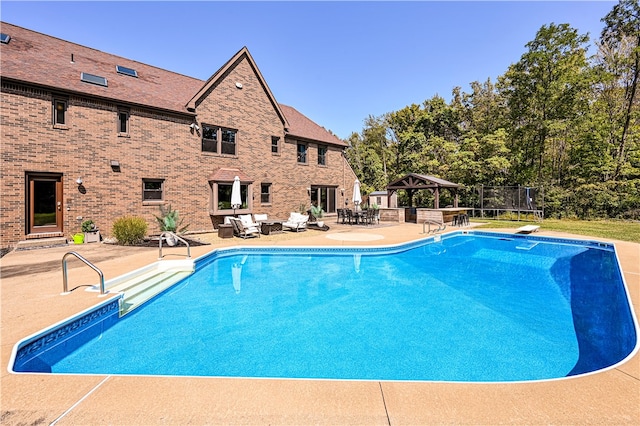 view of swimming pool with a gazebo, a diving board, and a patio area