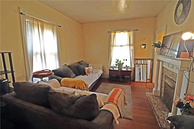 living area featuring a high end fireplace, a healthy amount of sunlight, and wood finished floors