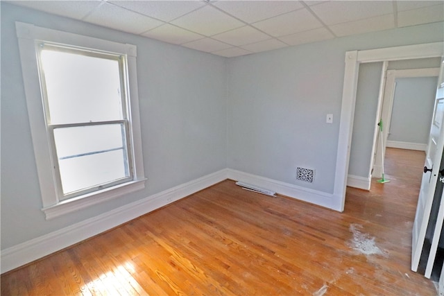 unfurnished room featuring light hardwood / wood-style flooring and a drop ceiling