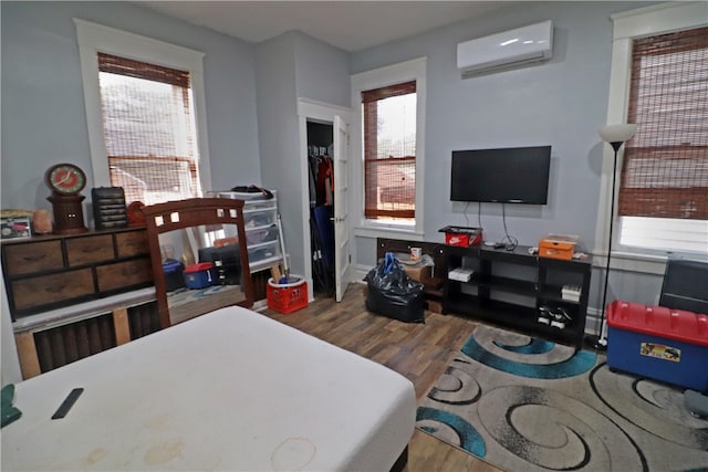 living room featuring a healthy amount of sunlight, hardwood / wood-style floors, and a wall unit AC