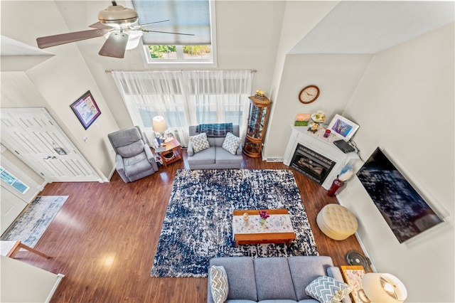 living room with a high ceiling, ceiling fan, and dark hardwood / wood-style flooring