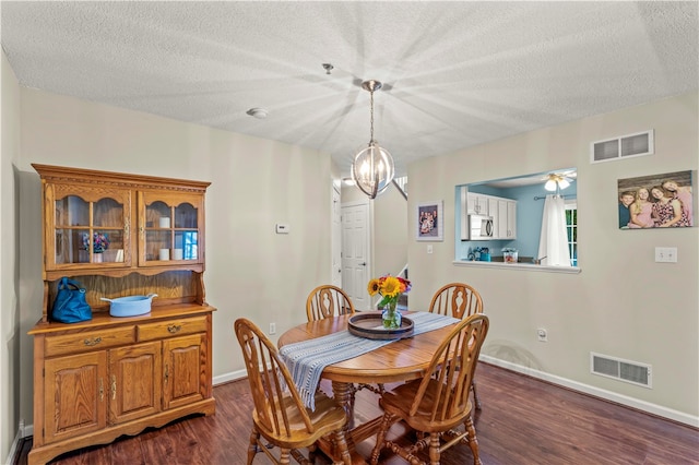 dining room featuring a textured ceiling, dark hardwood / wood-style floors, and ceiling fan with notable chandelier