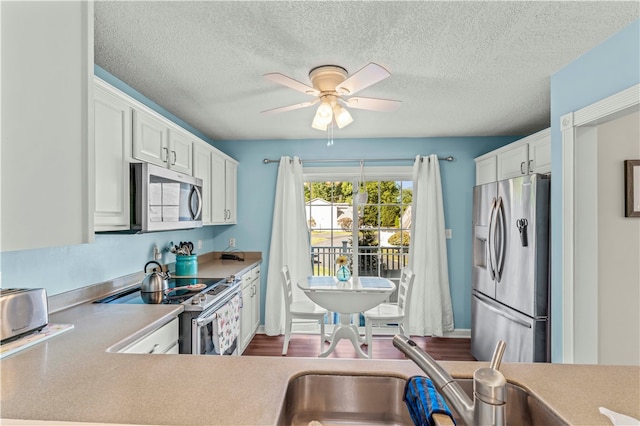 kitchen featuring white cabinetry, a textured ceiling, ceiling fan, dark wood-type flooring, and appliances with stainless steel finishes