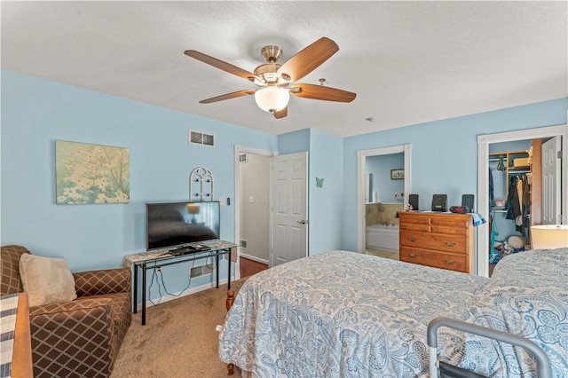 carpeted bedroom featuring a textured ceiling, ceiling fan, a walk in closet, and a closet