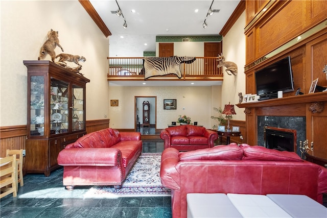 living room featuring a high ceiling, rail lighting, a high end fireplace, and crown molding