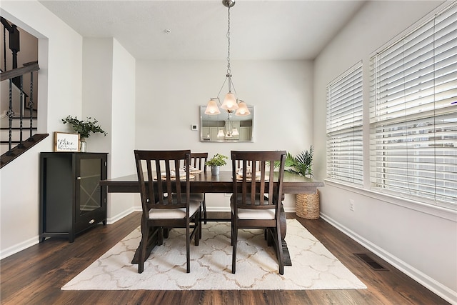 dining space featuring dark wood-type flooring and a chandelier