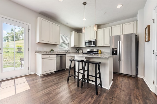 kitchen with dark wood-type flooring, plenty of natural light, a kitchen island, and stainless steel appliances