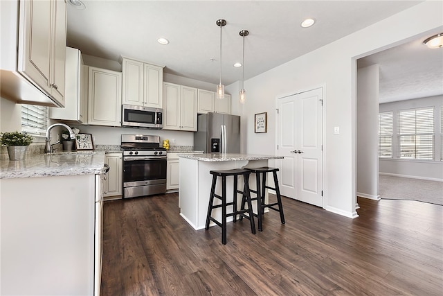 kitchen featuring a center island, stainless steel appliances, dark hardwood / wood-style floors, pendant lighting, and a kitchen bar